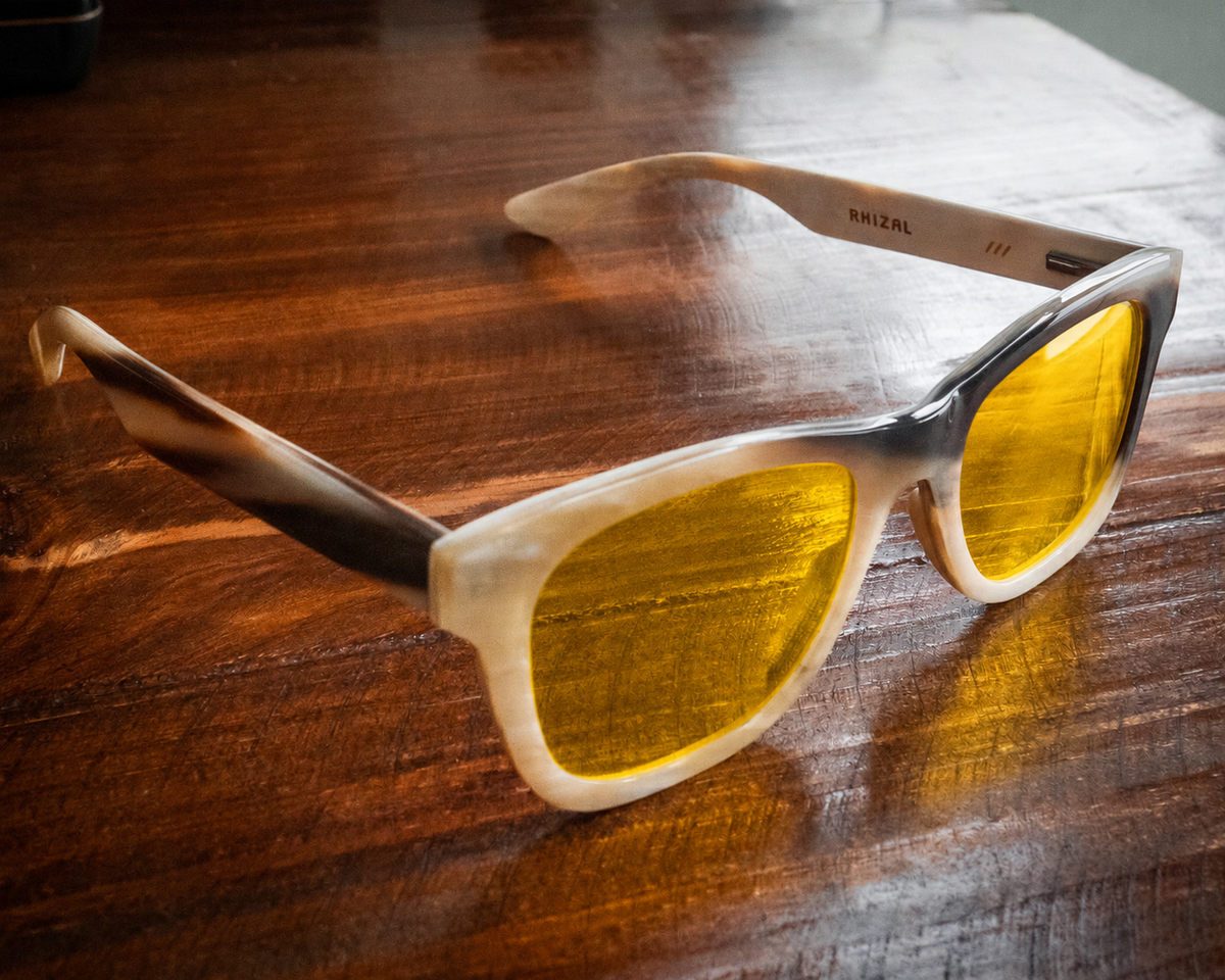 RHIZAL frame 432 in light buffalo horn with yellow day lenses on a wooden table